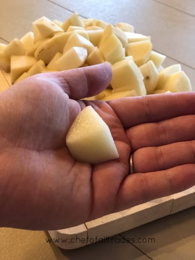 Diced potatoes with one in hand to show scale
