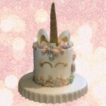 unicorn cake from cake tutorial on a white platter with a glitter background.