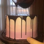 Silky Smooth Chocolate Ganache being pour over a pink cake