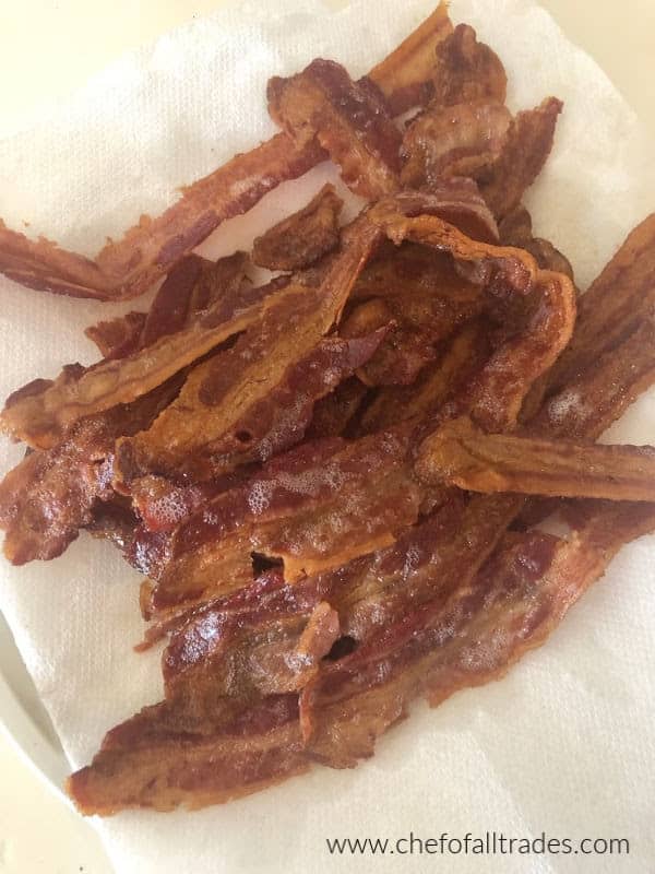 crispy cooked bacon draining on a paper towel lined plate