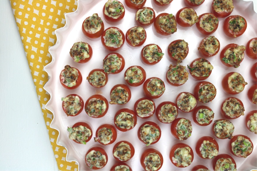 Bacon Stuffed Cherry Tomatoes in a white platter on a yellow and white tea towel