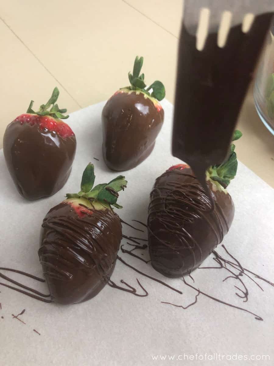 chocolate being drizzled over Chocolate covered strawberries using a fork