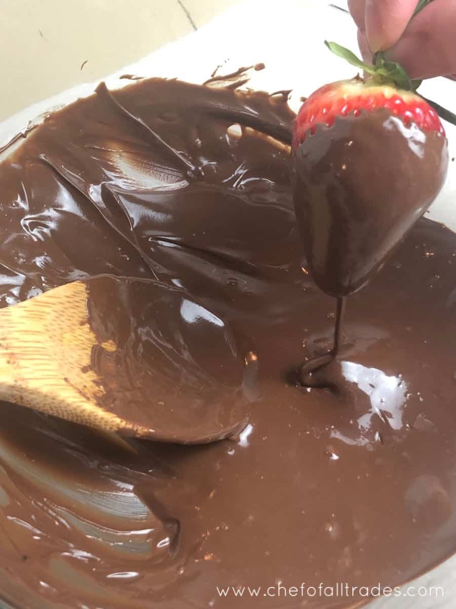 strawberry being dipped in melted chocolate