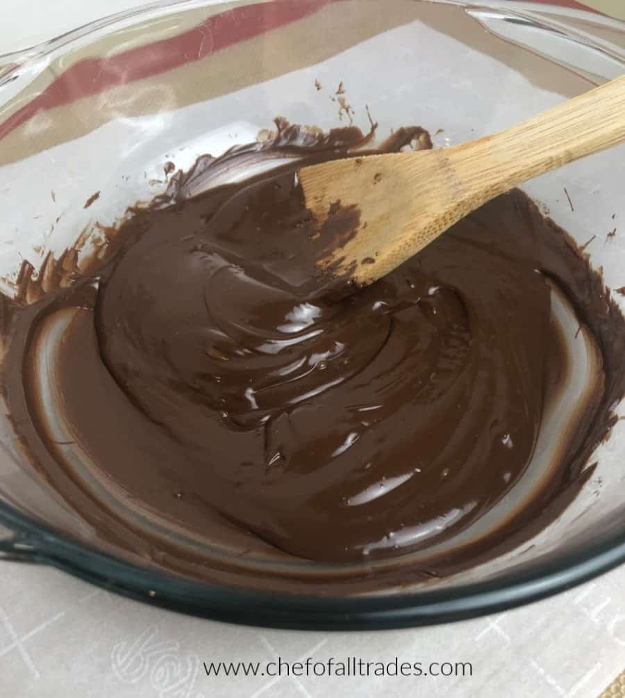 melted chocolate in a glass bowl with a wooden spoon