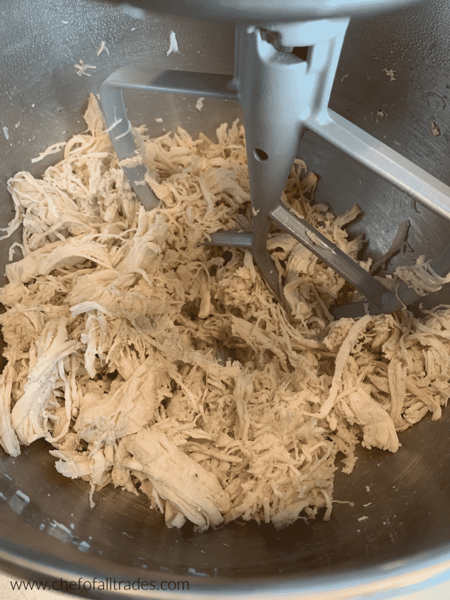 shredded chicken in a mixing bowl with paddle attachment