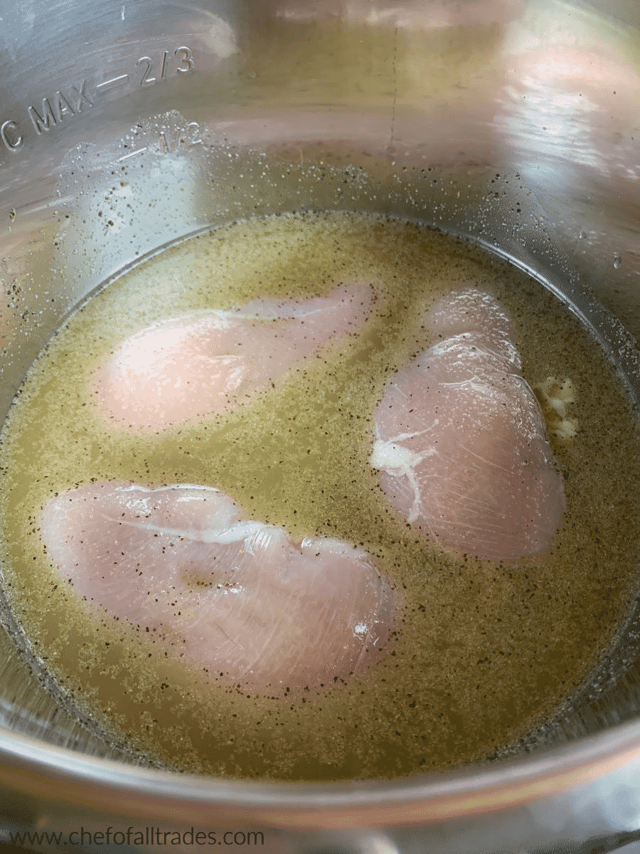 raw chicken in chicken stock with spices in an instant pot