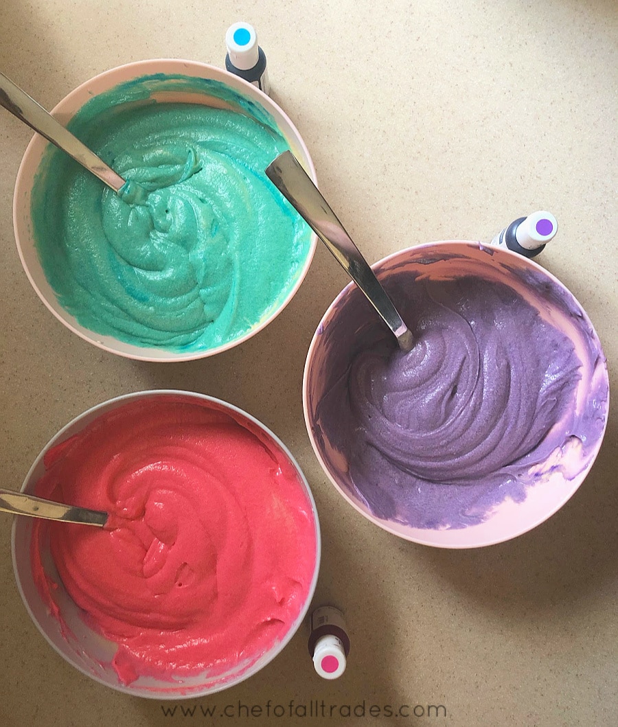 3 bowls of cake batter one teal, one purple and one pink