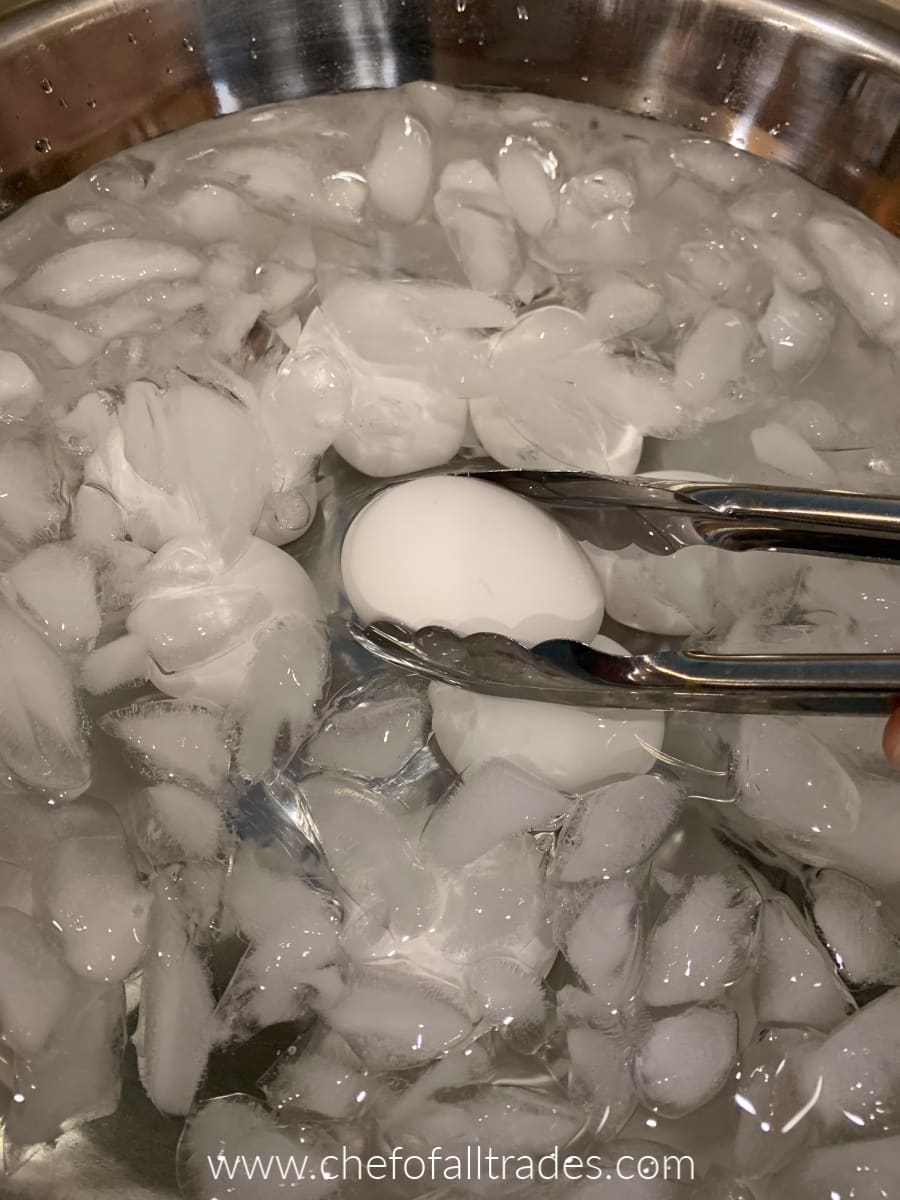transferring hardboiled eggs to a bowl full of ice water