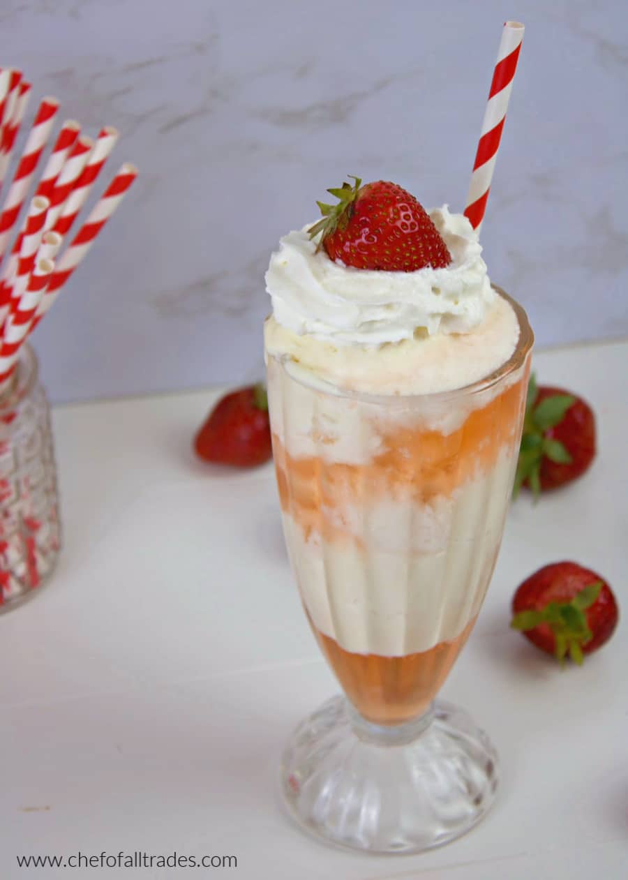 Strawberry Ice Cream Soda with whipped cream and strawberry garnish on a white counter top
