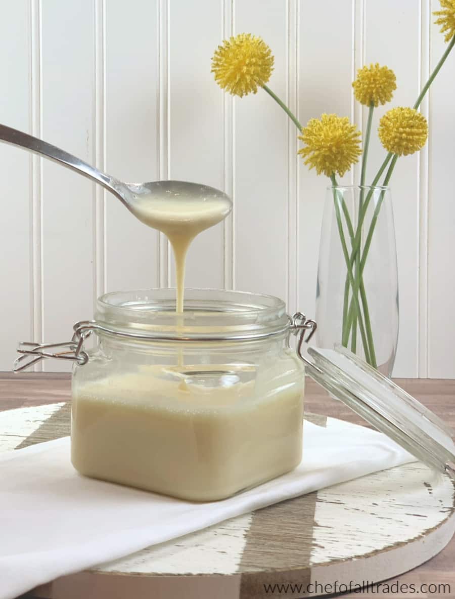 Sugar-Free Sweetened Condensed Milk in a glass mason jar with a glass lid on a cutting board and yellow flowers in the background