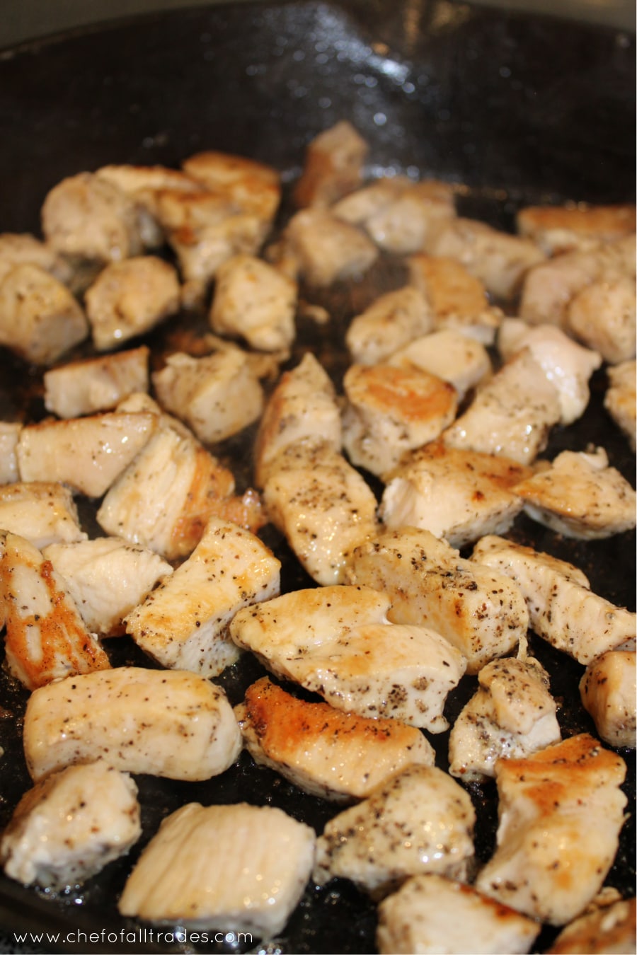 diced chicken in a skillet being browned