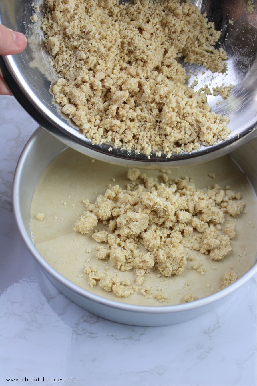 all crust ingredients mixed together in a silver bowl being poured into the cake pan