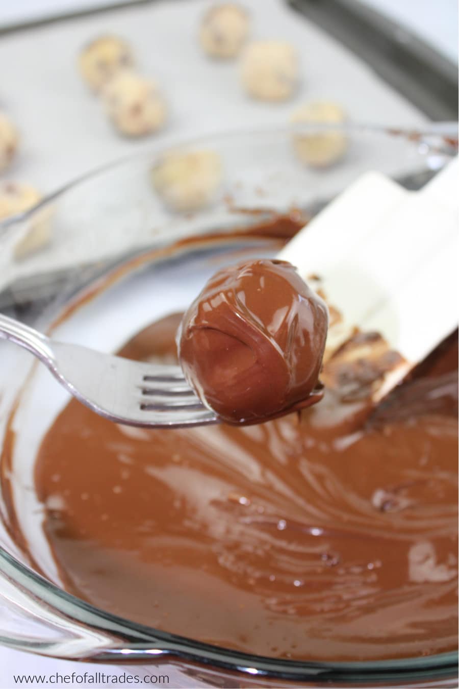 Chocolate Chip Cookie Dough ball covered in chocolate on the end of a fork